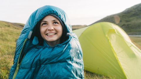 Ultraleicht Schlafsack: Junge Frau sitzt im Ultraleicht-Schlafsack vor einem Zelt