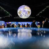 Menschen stehen bei der UN-Klimakonferenz COP26 unter einem Globus