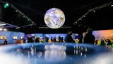 Menschen stehen bei der UN-Klimakonferenz COP26 unter einem Globus
