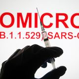 Eine Hand hält vor der Aufschrift "Omicron (B.1.1.529): SARS-CoV-2" eine Spritze hoch