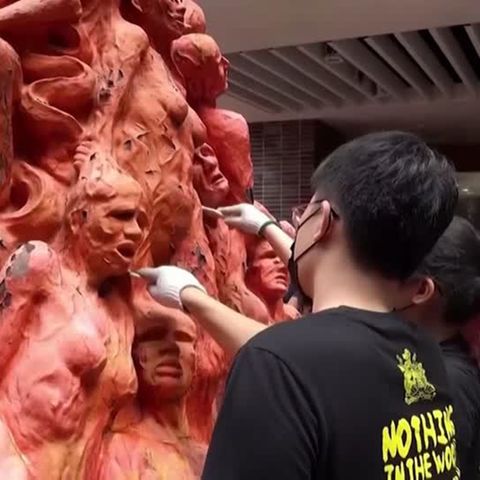 Künstler mit Spachteln bei der Arbeit an einem Denkmal mit vielen roten Figuren