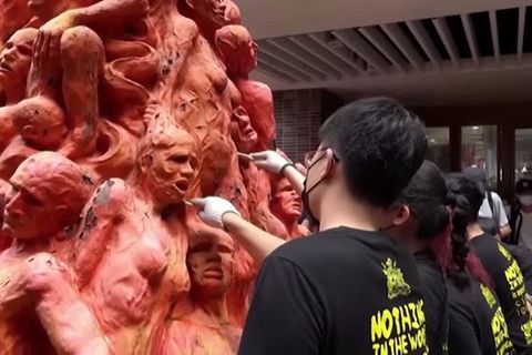 Künstler mit Spachteln bei der Arbeit an einem Denkmal mit vielen roten Figuren