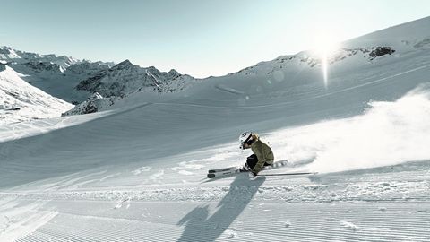 Jemand fährt auf Ski rasant eine verschneite Piste hinunter
