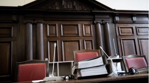 Gerichtsakten liegen auf dem Richtertisch in einem Gerichtssaal