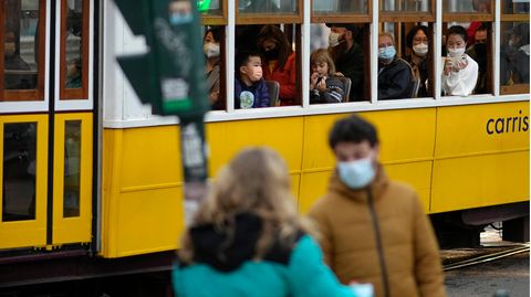 Menschen mit Mund-Nasen-Schutz fahren in einer Straßenbahn