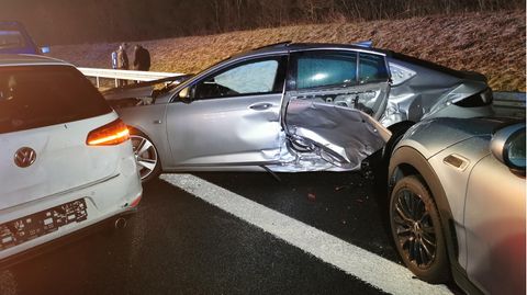 Links steht ein weißer Wagen mit eingedrücktem Heck, schräg auf dem Randstreifen ein silberner mit verbeulter Seitentür
