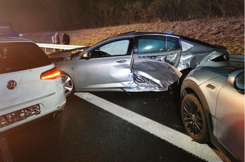 Links steht ein weißer Wagen mit eingedrücktem Heck, schräg auf dem Randstreifen ein silberner mit verbeulter Seitentür