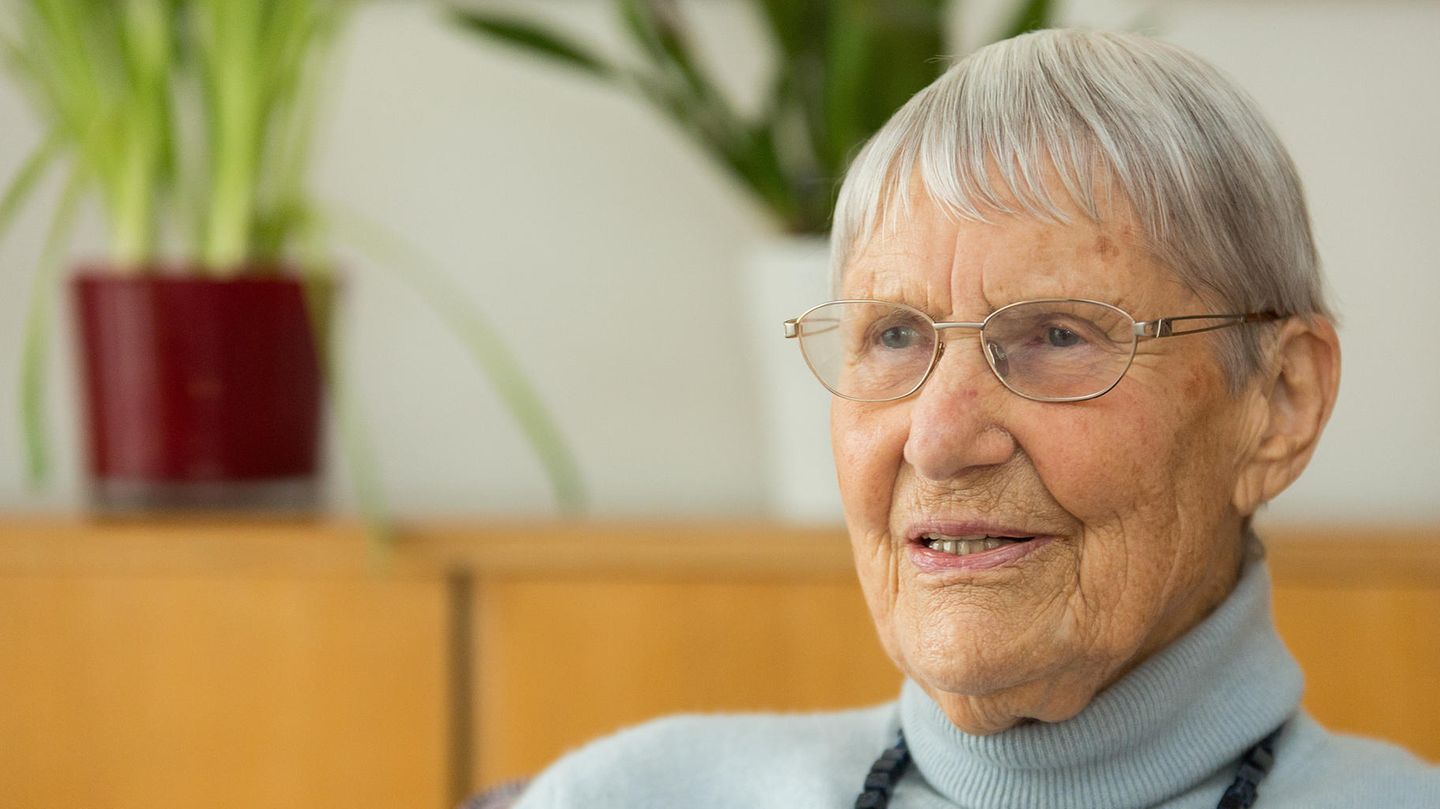 Inge Jens sitzt in hellblauem Rollkragen-Pullover da und spricht