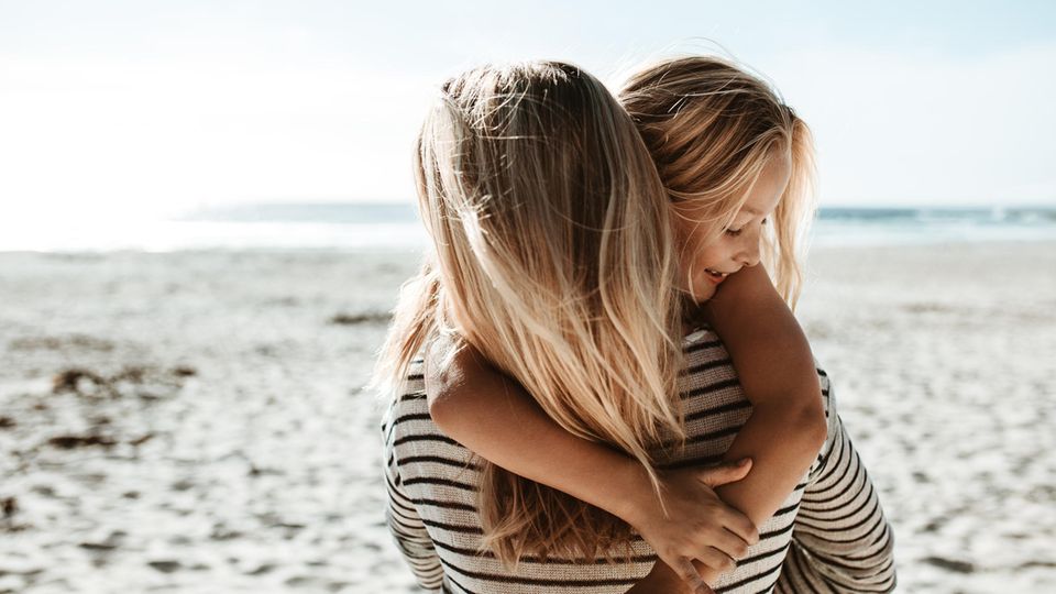 Symbolbild Regretting Motherhood: Eine Mutter umarmt ihre Tochter