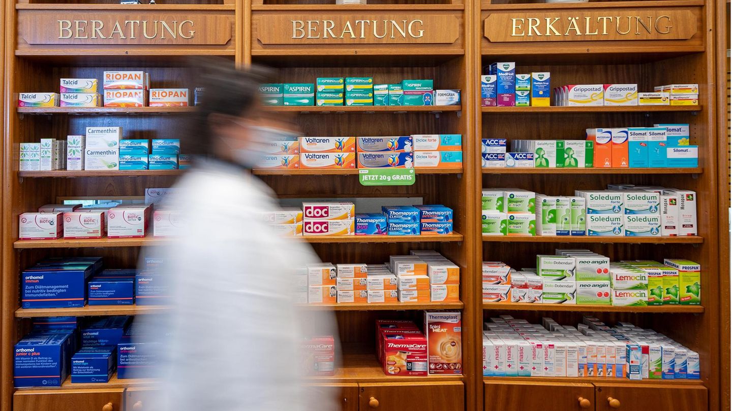 Eine Apothekerin steht vor einem mit Medikamenten befüllten Regal