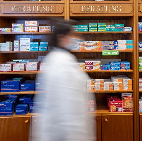 Eine Apothekerin steht vor einem mit Medikamenten befüllten Regal