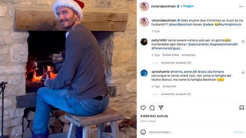 David Beckham sitzt mit einer Weihnachtsmannmütze vor einem Kamin