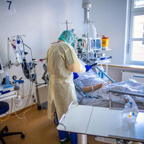 Eine Pflegekraft betreut auf einer Intensivstation einen Corona-Patienten.