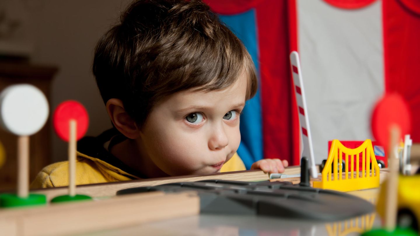 Ein kleiner Junge spielt mit einer Spielzeug-Eisenbahn