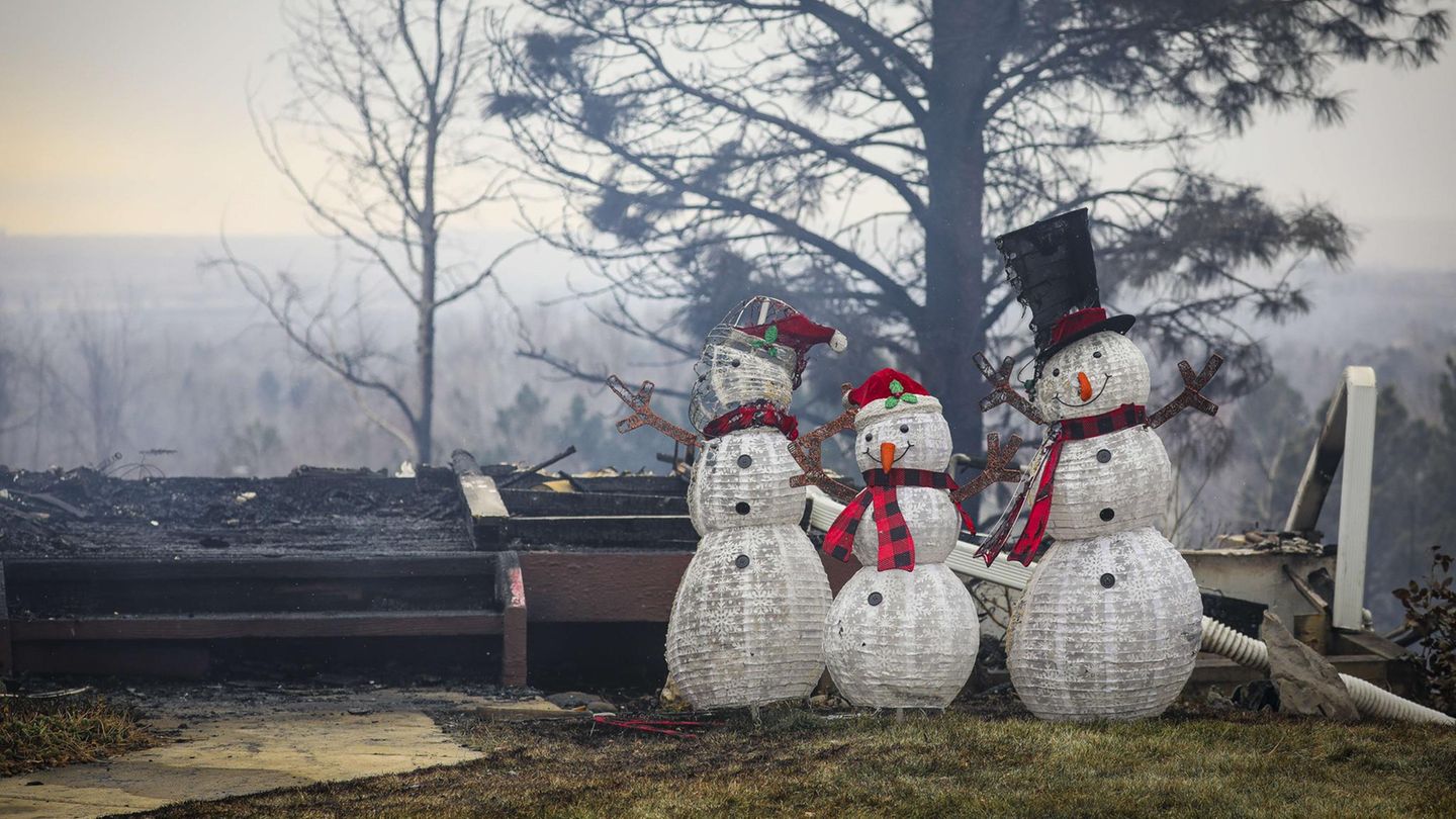 Schneemänner stehen neben den Überresten eines Hauses