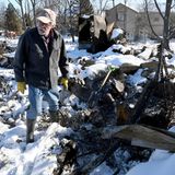 Ein Mann durchwühlt die Trümmer seines abgebrannten Hauses