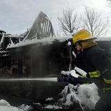 Superior, USA. Ein Feuerwehrmann sprüht Wasser in ein schneebedecktes Haus, in dem noch immer Glut vom "Marshall Feuer" glüht. 