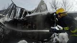 Superior, USA. Ein Feuerwehrmann sprüht Wasser in ein schneebedecktes Haus, in dem noch immer Glut vom "Marshall Feuer" glüht. 