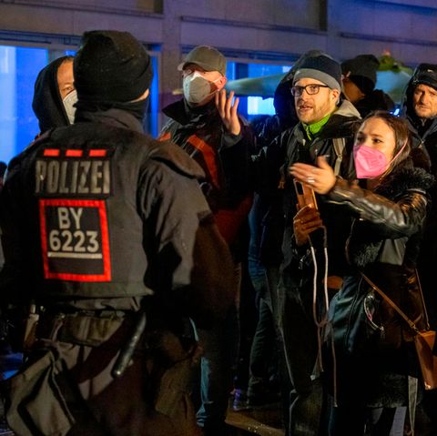 Demonstranten eines unangemeldeten sogenannten Corona-Spaziergangs in München diskutieren aufgebracht mit Polizisten