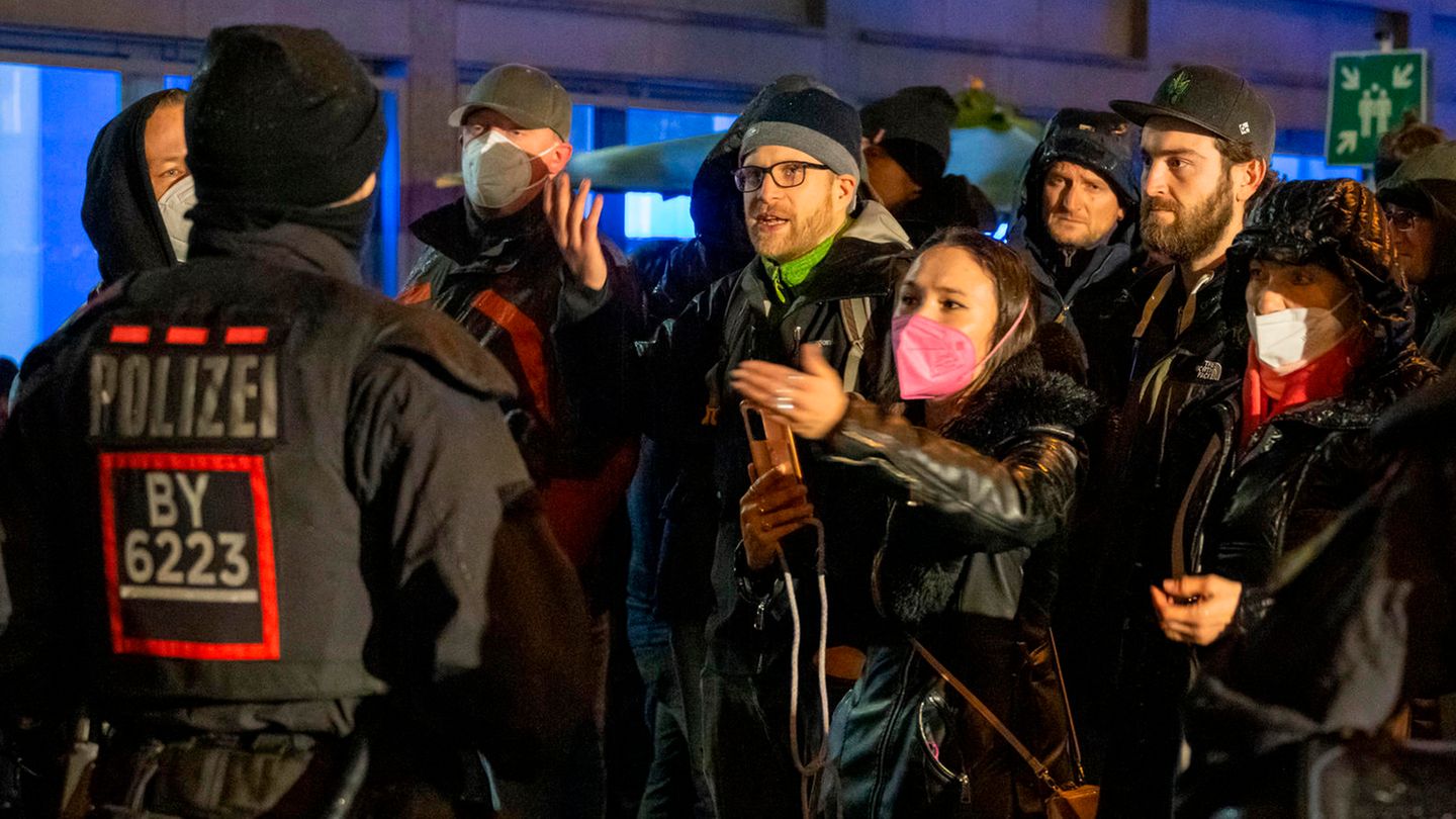 Demonstranten eines unangemeldeten sogenannten Corona-Spaziergangs in München diskutieren aufgebracht mit Polizisten