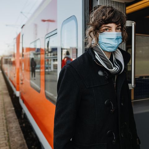 Eine Frau mit Maske steigt in einen Zug