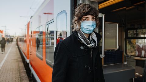 Eine Frau mit Maske steigt in einen Zug