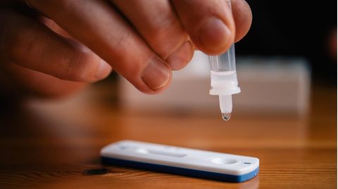 Ein Mann träufelt eine Lösung auf die Testkassette eines Coronavirus-Selbsttests