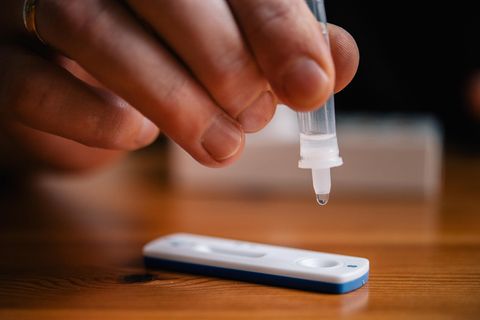 Ein Mann träufelt eine Lösung auf die Testkassette eines Coronavirus-Selbsttests