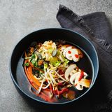 Pho mit Gartengemüse      Zutaten:  Für die Brühe: 2 Bio-Zwiebeln, 3 Bio-Knoblauchzehen, 10 cm Bio-Ingwer, 4 EL Zucker, 2 Szechuan-Pfefferkörner (ersatzweise 5 Pfefferkörner), 2 Sternanis, ½ Zimtstange, 2 l Gemüsebrühe, 70 ml Teriyakisauce (ersatzweise Sojasauce)  Für die Einlage: 150 g braune Champignons, 2 Möhren, 3 Frühlingszwiebeln, 4 EL Sprossen, 3 Stängel Koriandergrün, 2 Stängel frische Minze, 250 g eifreie Mienudeln (ersatzweise Reisnudeln), 4 TL geröstetes Sesamöl, 4 EL Röstzwiebeln, 4 TL Kürbiskerne (ersatzweise Sonnenblumenkerne), fermentierte Chilisauce (nach Belieben)      Zubereitung:  1. Die Zwiebeln mit Schale vierteln, den Knoblauch mit Schale an - drücken, den Ingwer mit Schale in dünne Scheiben schneiden (falls keine Bio-Zutaten zur Hand sind, sollten Zwiebeln, Knoblauch und Ingwer geschält werden).  2. Zwiebeln, Ingwer und Knoblauch in einem Topf ohne Öl anrösten, bis diese rundherum schön braun geworden sind. Zucker dazugeben und goldbraun karamellisieren. Szechuan-Pfeffer, Sternanis, Zimt, Gemüsebrühe sowie Teriyakisauce dazugeben und auf mittlerer Stufe mit halb aufgelegtem Deckel 30 Min. köcheln lassen. Anschlie - ßend die Suppe vom Herd ziehen, durch ein feines Sieb abgießen und die Brühe dabei auffangen. Die Brühe warm halten.  3. Für die Einlage die Champignons putzen und in feine Scheiben schneiden. Die Möhren schälen und mit dem Sparschäler in lange, feine Streifen schneiden. Die Frühlingszwiebeln, Sprossen und Kräuter waschen und trocknen. Die Zwiebeln in sehr feine Ringe schneiden, die Kräuter fein hacken.  4. Die Mienudeln nach Packungsanweisung gar kochen, abgießen, mit dem Sesamöl vermengen und auf vier tiefe Schüsseln verteilen. Die Brühe zum Kochen bringen. Das Gemüse ebenfalls auf die Schüs - seln verteilen, dann die kochend heiße Brühe angießen. Sprossen, Kräuter, Röstzwiebeln, Kürbiskerne und Chilisauce nach Belieben über die Suppe geben und sofort servieren