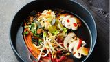 Pho mit Gartengemüse      Zutaten:  Für die Brühe: 2 Bio-Zwiebeln, 3 Bio-Knoblauchzehen, 10 cm Bio-Ingwer, 4 EL Zucker, 2 Szechuan-Pfefferkörner (ersatzweise 5 Pfefferkörner), 2 Sternanis, ½ Zimtstange, 2 l Gemüsebrühe, 70 ml Teriyakisauce (ersatzweise Sojasauce)  Für die Einlage: 150 g braune Champignons, 2 Möhren, 3 Frühlingszwiebeln, 4 EL Sprossen, 3 Stängel Koriandergrün, 2 Stängel frische Minze, 250 g eifreie Mienudeln (ersatzweise Reisnudeln), 4 TL geröstetes Sesamöl, 4 EL Röstzwiebeln, 4 TL Kürbiskerne (ersatzweise Sonnenblumenkerne), fermentierte Chilisauce (nach Belieben)      Zubereitung:  1. Die Zwiebeln mit Schale vierteln, den Knoblauch mit Schale an - drücken, den Ingwer mit Schale in dünne Scheiben schneiden (falls keine Bio-Zutaten zur Hand sind, sollten Zwiebeln, Knoblauch und Ingwer geschält werden).  2. Zwiebeln, Ingwer und Knoblauch in einem Topf ohne Öl anrösten, bis diese rundherum schön braun geworden sind. Zucker dazugeben und goldbraun karamellisieren. Szechuan-Pfeffer, Sternanis, Zimt, Gemüsebrühe sowie Teriyakisauce dazugeben und auf mittlerer Stufe mit halb aufgelegtem Deckel 30 Min. köcheln lassen. Anschlie - ßend die Suppe vom Herd ziehen, durch ein feines Sieb abgießen und die Brühe dabei auffangen. Die Brühe warm halten.  3. Für die Einlage die Champignons putzen und in feine Scheiben schneiden. Die Möhren schälen und mit dem Sparschäler in lange, feine Streifen schneiden. Die Frühlingszwiebeln, Sprossen und Kräuter waschen und trocknen. Die Zwiebeln in sehr feine Ringe schneiden, die Kräuter fein hacken.  4. Die Mienudeln nach Packungsanweisung gar kochen, abgießen, mit dem Sesamöl vermengen und auf vier tiefe Schüsseln verteilen. Die Brühe zum Kochen bringen. Das Gemüse ebenfalls auf die Schüs - seln verteilen, dann die kochend heiße Brühe angießen. Sprossen, Kräuter, Röstzwiebeln, Kürbiskerne und Chilisauce nach Belieben über die Suppe geben und sofort servieren