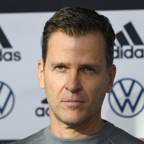 Oliver Bierhoff vor einer Werbetafel, ein Schatten bedeckt die eine Hälfte seines Gesichts