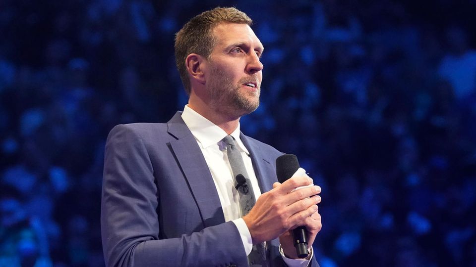 Dirk Nowitzki trägt einen Anzug und hält ein Mikrofon in der Hand
