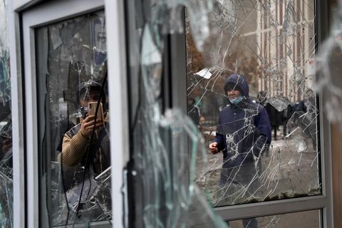 Ein Mann fotografiert Fenster, die von Teilnehmern einer Demonstration beschädigt wurden