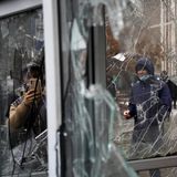 Ein Mann fotografiert Fenster, die von Teilnehmern einer Demonstration beschädigt wurden