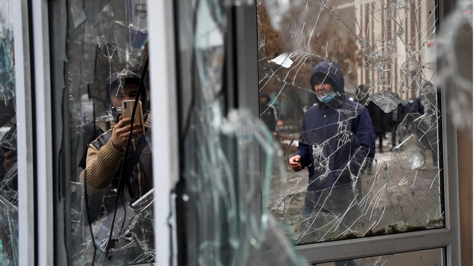 Ein Mann fotografiert Fenster, die von Teilnehmern einer Demonstration beschädigt wurden