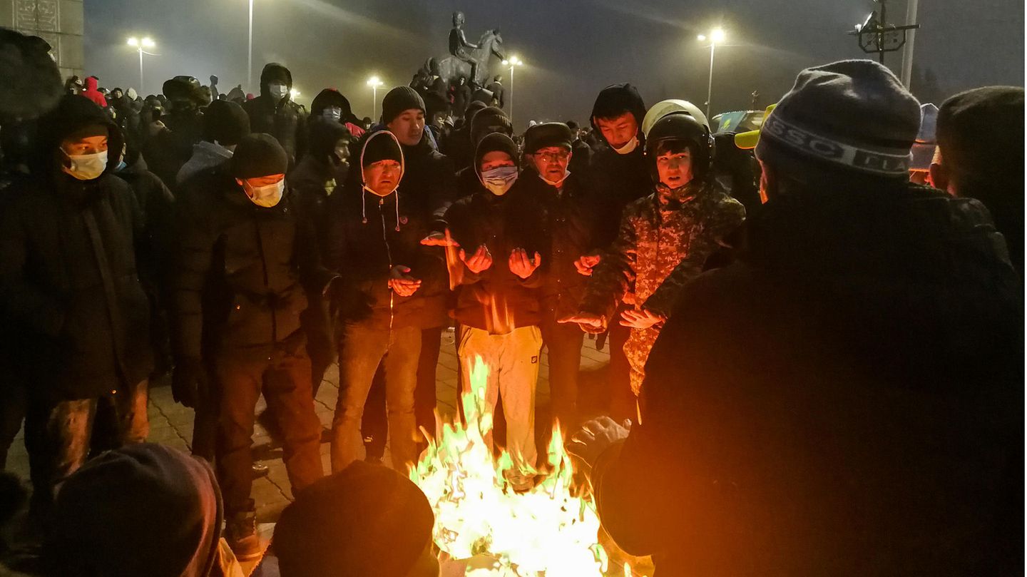 Menschen, die an einer Kundgebung teilnehmen und sich an einem Feuer wärmen.