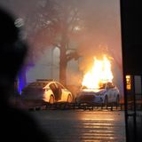 Ein Polizeiauto steht in Flammen. 