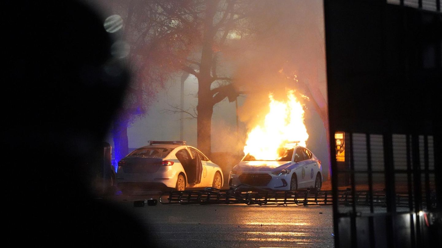 Ein Polizeiauto steht in Flammen. 