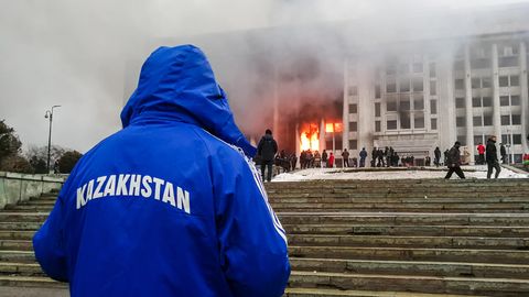 Mann steht mit Kasachstan-Jacke abseits der Proteste