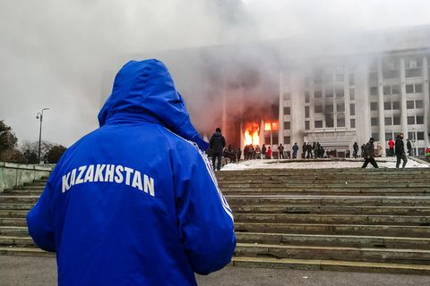Mann steht mit Kasachstan-Jacke abseits der Proteste