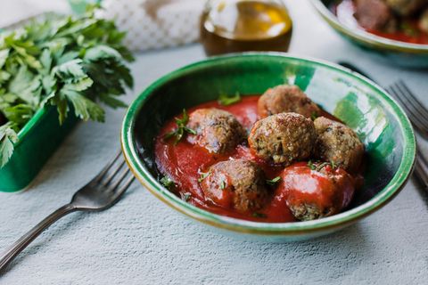 Vegane Frikadellen in einer grünen Schüssel mit Tomatensoße