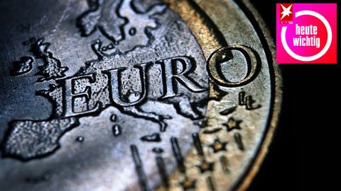 Auf einem schwarzen Untergrund liegt eine Ein-Euro-Münze mit Kratzern und Gebrauchsspuren