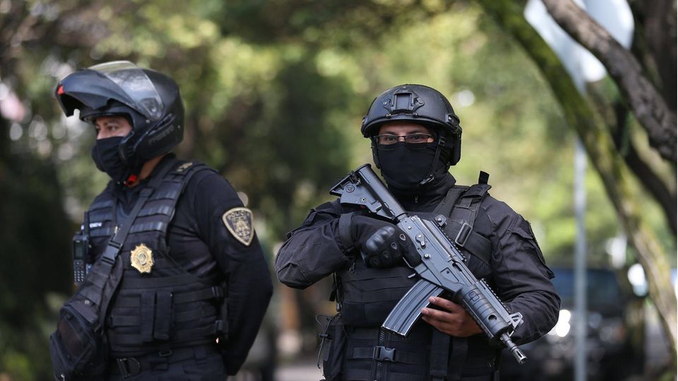 Zwei Polizisten, einer mit einer Maschinenpistole bewaffnet, stehen nebeneinander