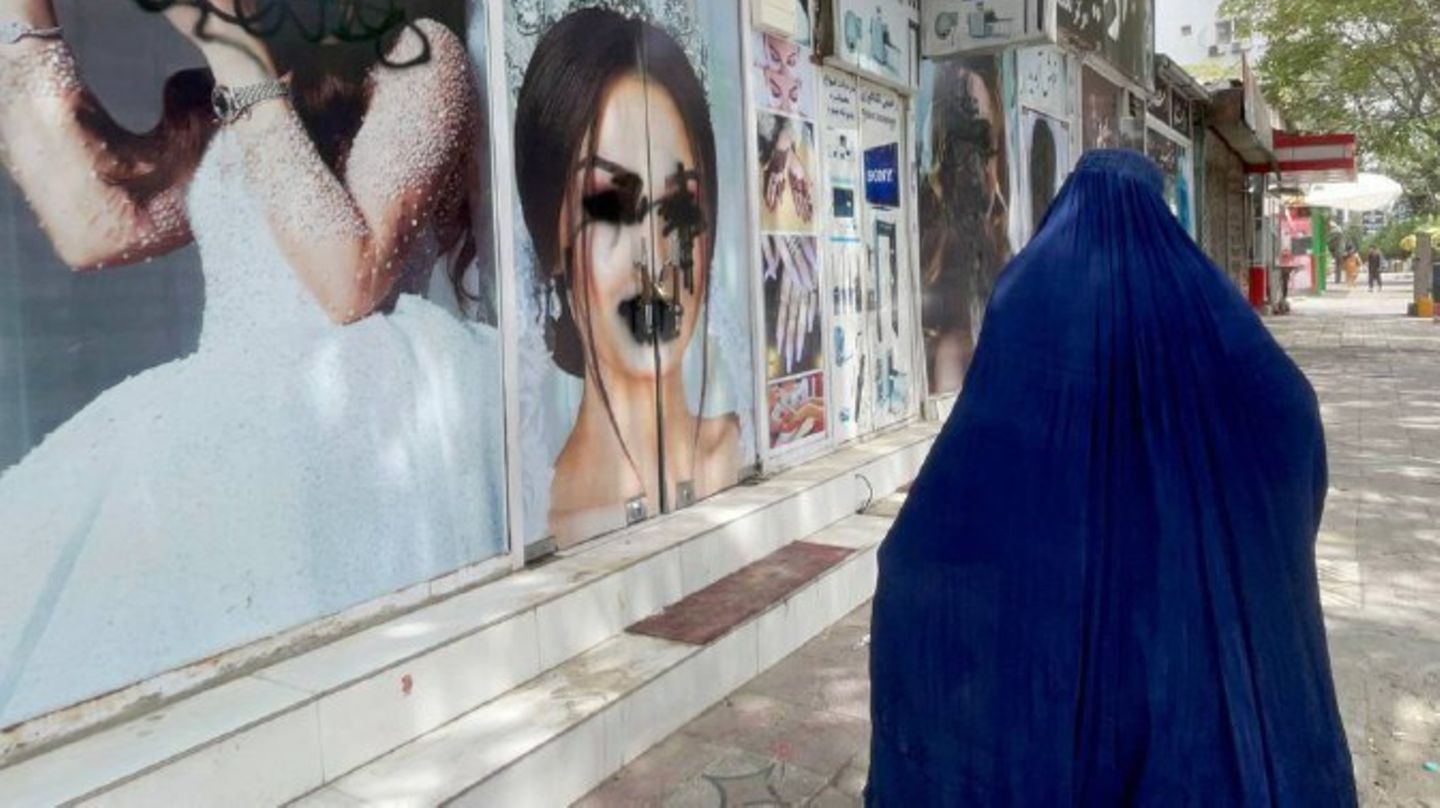 Eine Frau mit Burka geht in Kabul in Afghanistan an einem Schönheitssalon vorbei, dessen Fenster beschmiert worden sind