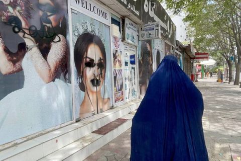 Eine Frau mit Burka geht in Kabul in Afghanistan an einem Schönheitssalon vorbei, dessen Fenster beschmiert worden sind