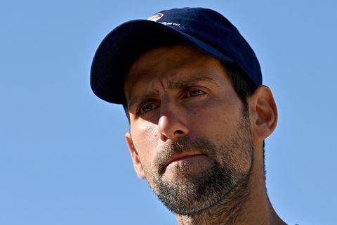 Ein weißer Mann mit dunklem Drei-Tage-Bart und blauem Cap schaut ernst, während er vor blauem Himmel steht