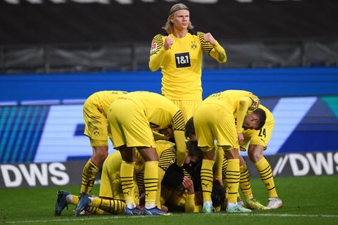 Während mehrere Fußballer in gelben Trikots und Hosen sich über einen am Boden Jubelnden beugen, steht einer aufrecht
