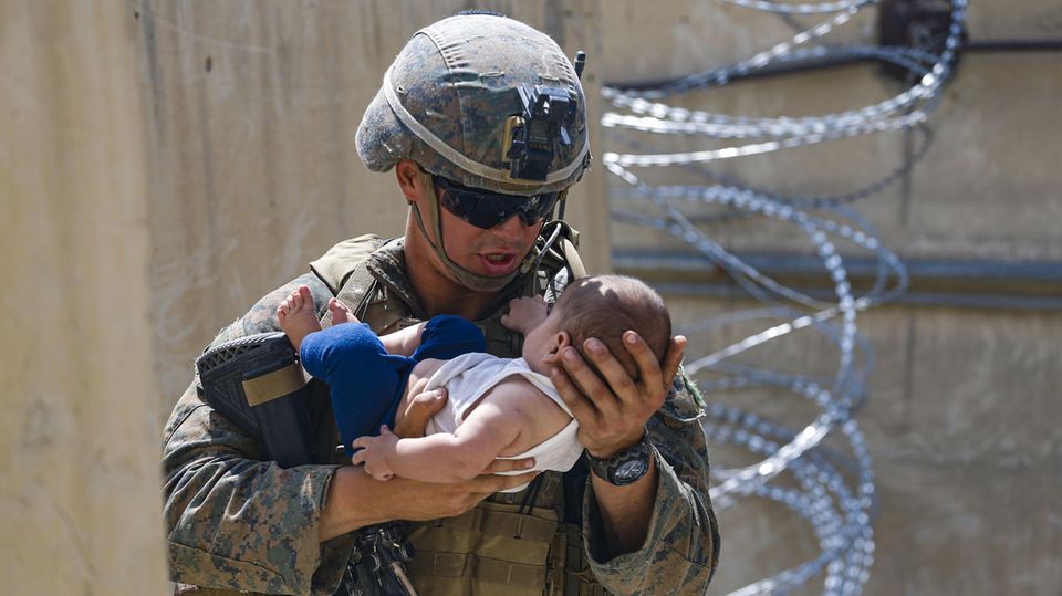 Kabul, Afghanistan: Ein US-Soldat bekommt während des Chaos am Flughafen ein Baby in die Arme gedrückt.