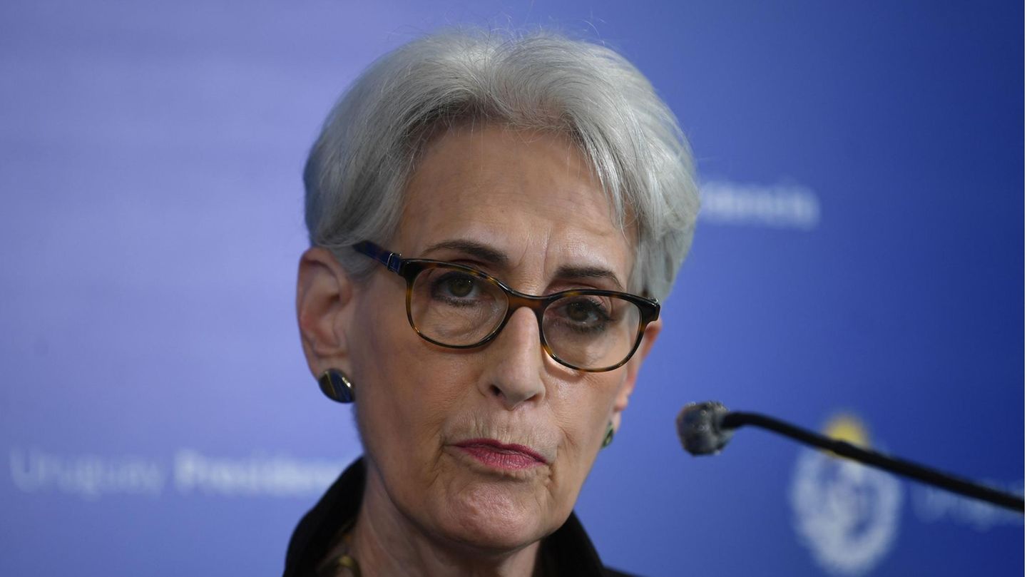 Eine älter weiße Frau mit kurzen, grau-weißen Haaren und Hornbrille hört einer Frage zu