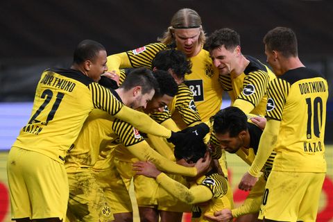 Eine Traube Fußballer in gelb-schwarz umringen jubelnd einen Mitspieler, der in ihrer Mitte zu Boden sinkt